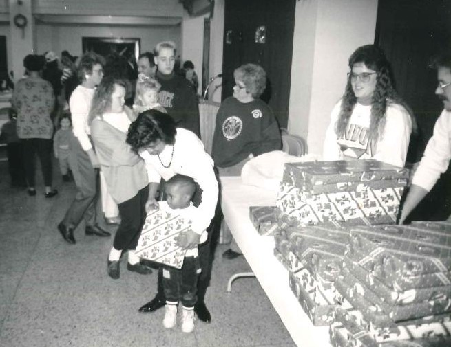 Christmas party showing mom handing child a wrapped gift